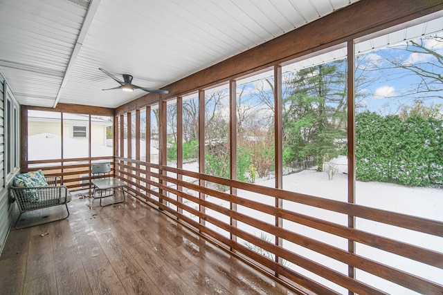 sunroom / solarium featuring beamed ceiling and ceiling fan