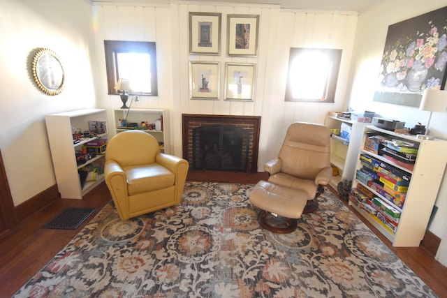 living area featuring a fireplace, a healthy amount of sunlight, and dark wood-type flooring