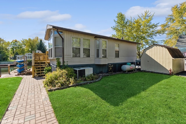 rear view of house with a yard and a storage shed