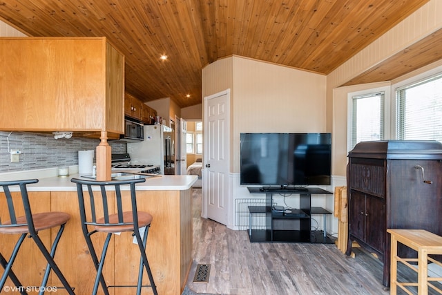 kitchen featuring black appliances, dark hardwood / wood-style flooring, lofted ceiling, and kitchen peninsula