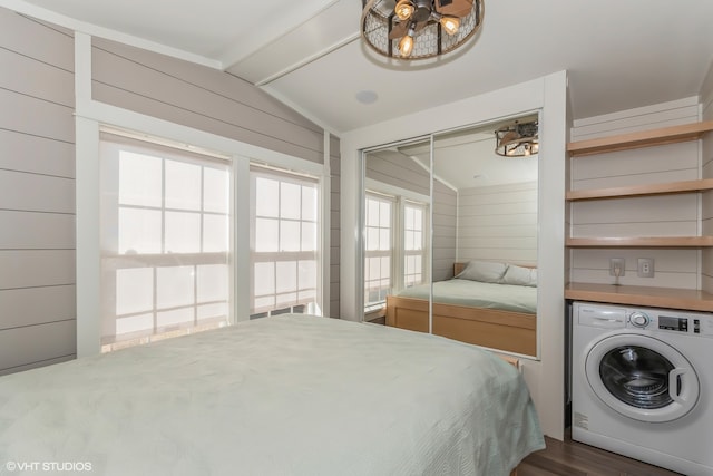 bedroom featuring washer / clothes dryer, wooden walls, and vaulted ceiling