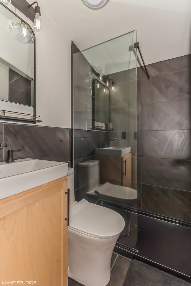 bathroom with a tile shower, vanity, and toilet