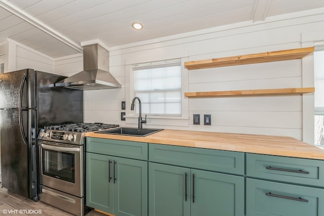 kitchen featuring wooden counters, sink, wall chimney range hood, hardwood / wood-style floors, and stainless steel gas stove