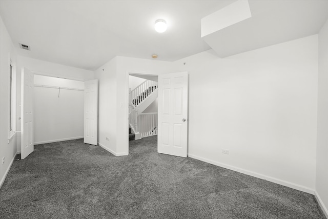 unfurnished bedroom featuring dark colored carpet and a closet