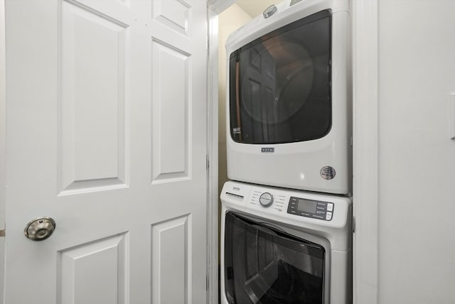 clothes washing area with stacked washing maching and dryer