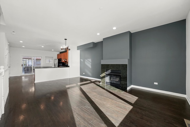 living room featuring dark hardwood / wood-style flooring, a fireplace, and an inviting chandelier