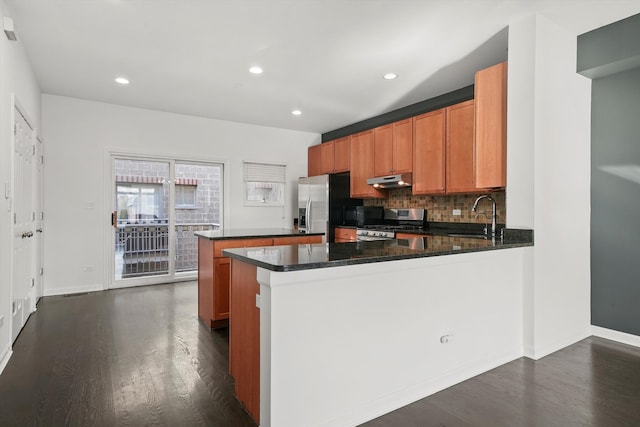 kitchen with dark stone counters, decorative backsplash, appliances with stainless steel finishes, a kitchen island, and dark hardwood / wood-style flooring