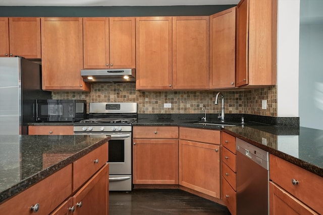 kitchen featuring stainless steel appliances, tasteful backsplash, dark stone countertops, and sink