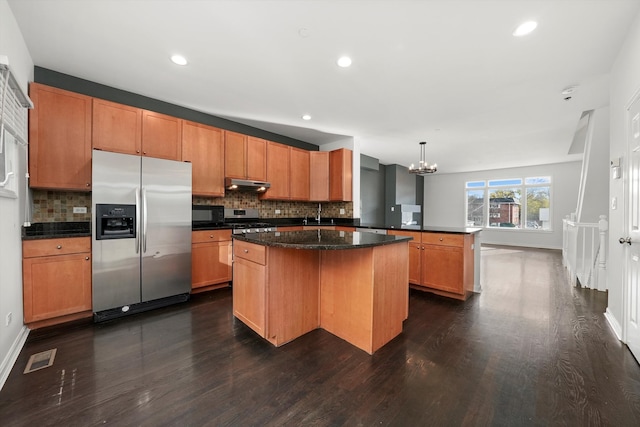 kitchen featuring a center island, hanging light fixtures, stainless steel appliances, tasteful backsplash, and dark hardwood / wood-style flooring