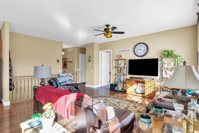 living room featuring baseboards, wood finished floors, visible vents, and ceiling fan