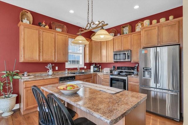 kitchen with light wood finished floors, appliances with stainless steel finishes, light countertops, and a sink