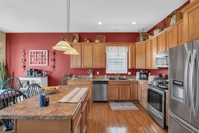 kitchen with pendant lighting, light wood-style flooring, a sink, appliances with stainless steel finishes, and light countertops