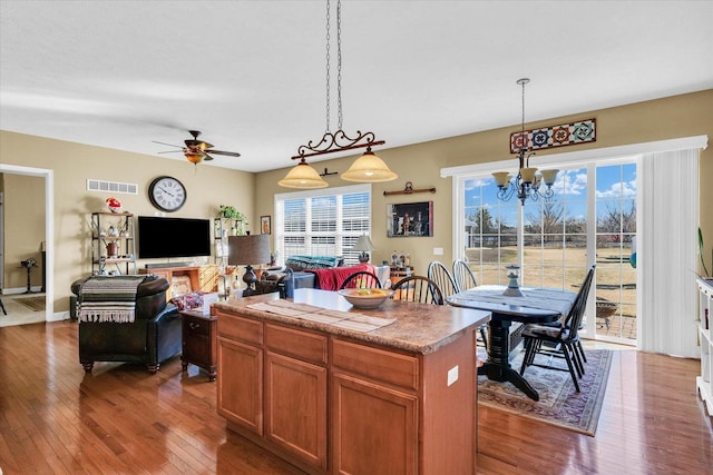 kitchen featuring visible vents, brown cabinets, pendant lighting, a kitchen island, and hardwood / wood-style floors