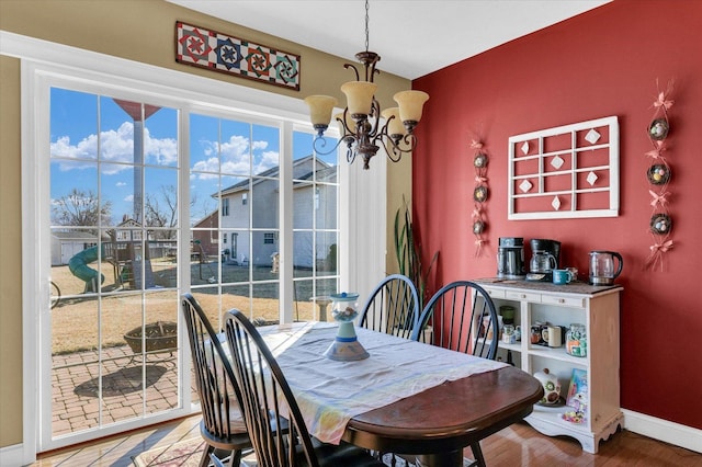 dining space with an inviting chandelier, wood finished floors, and baseboards