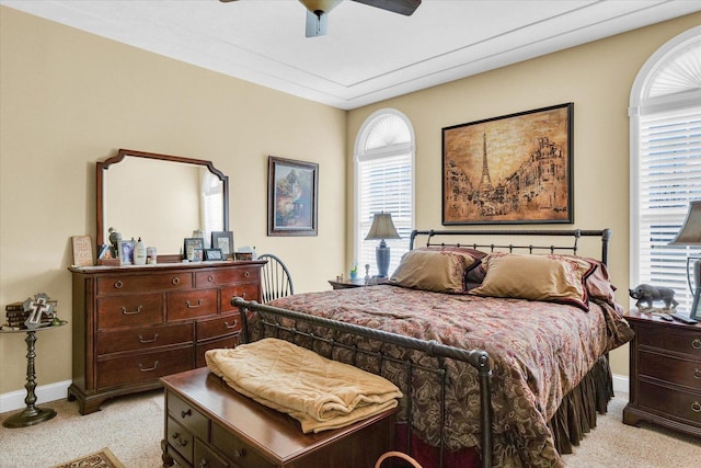 bedroom featuring multiple windows, light carpet, baseboards, and a ceiling fan