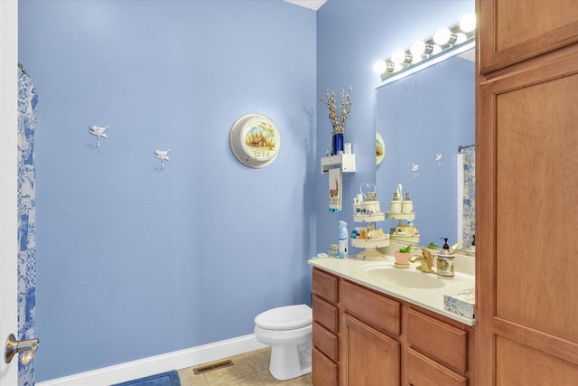 bathroom with vanity, toilet, visible vents, and baseboards