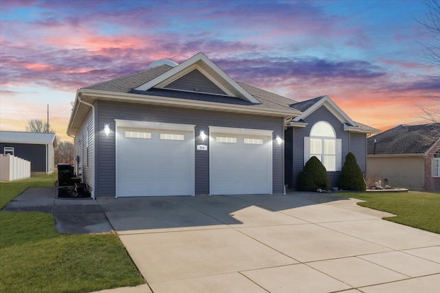 ranch-style house featuring driveway, a yard, roof with shingles, a garage, and central AC unit