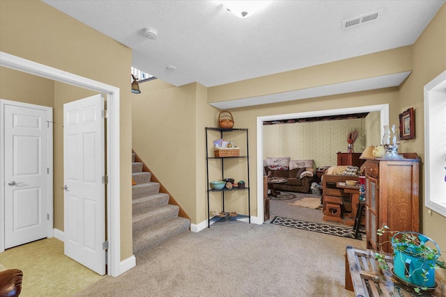 interior space featuring visible vents, baseboards, carpet, and a textured ceiling