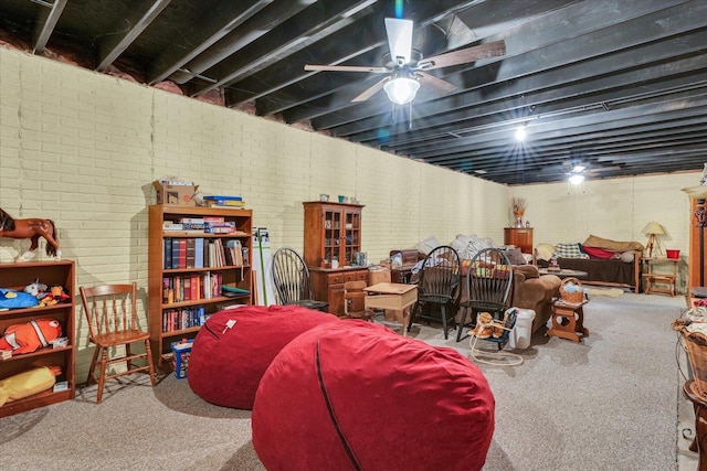 finished below grade area with carpet, brick wall, and a ceiling fan