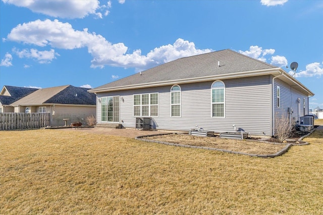 back of property featuring a yard, roof with shingles, central AC unit, and fence