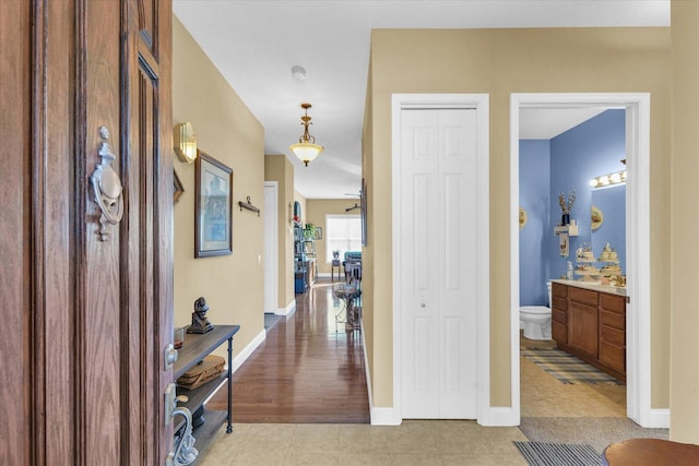 hall featuring baseboards and light tile patterned flooring