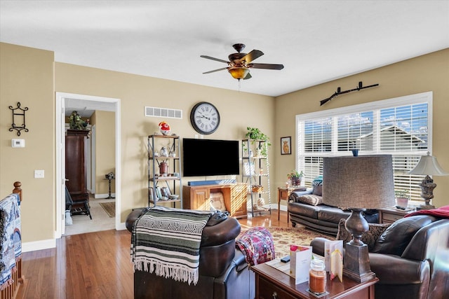 living area with visible vents, wood finished floors, baseboards, and ceiling fan