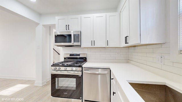 kitchen with sink, stainless steel appliances, tasteful backsplash, light hardwood / wood-style floors, and white cabinets