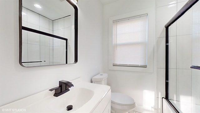 full bathroom featuring vanity, bath / shower combo with glass door, and toilet