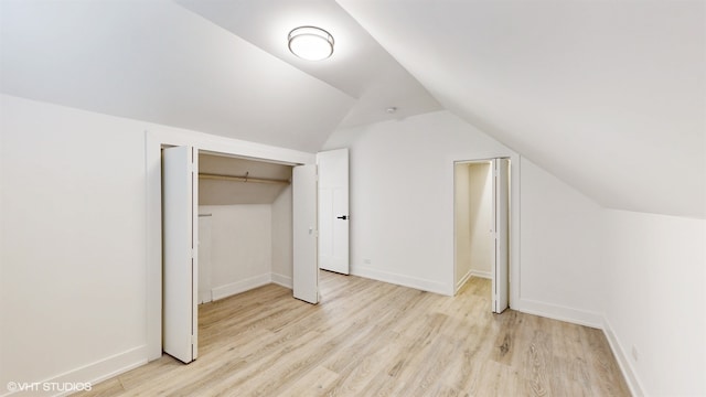 bonus room with light wood-type flooring and vaulted ceiling