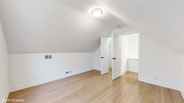 additional living space with light hardwood / wood-style floors and lofted ceiling