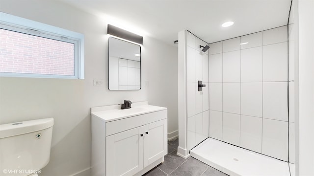 bathroom with a tile shower, tile patterned flooring, vanity, and toilet