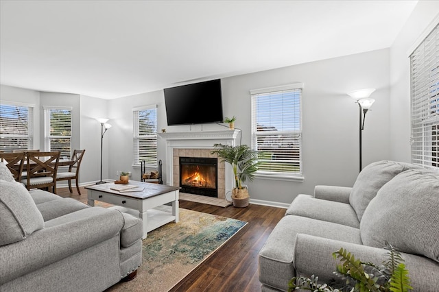 living room with dark hardwood / wood-style floors, plenty of natural light, and a tiled fireplace