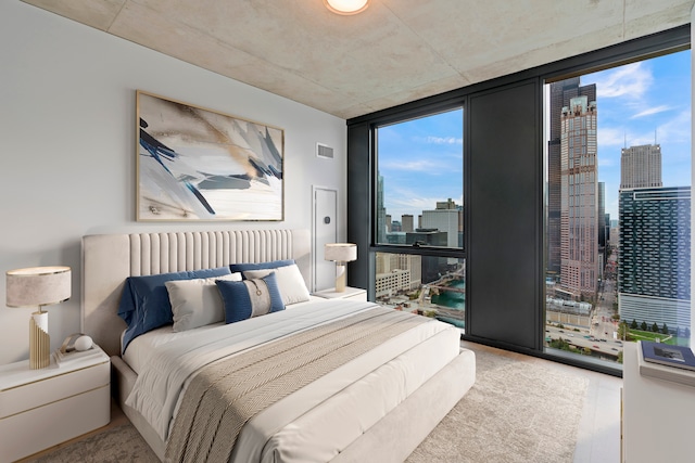 bedroom with floor to ceiling windows and light wood-type flooring