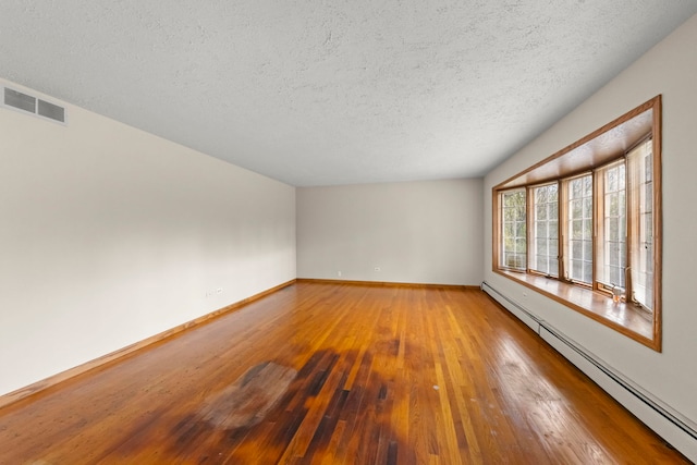 spare room with wood-type flooring, a textured ceiling, and a baseboard radiator