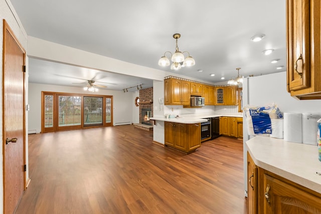 kitchen featuring hardwood / wood-style flooring, ceiling fan with notable chandelier, kitchen peninsula, and decorative light fixtures