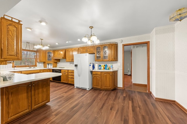 kitchen featuring decorative light fixtures, black oven, white fridge with ice dispenser, and dark hardwood / wood-style floors