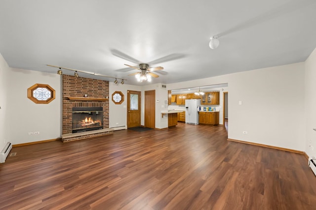 unfurnished living room with dark hardwood / wood-style floors, a baseboard heating unit, ceiling fan, and a brick fireplace