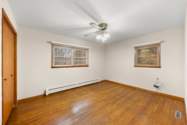 unfurnished bedroom with ceiling fan, a closet, wood-type flooring, and a baseboard heating unit