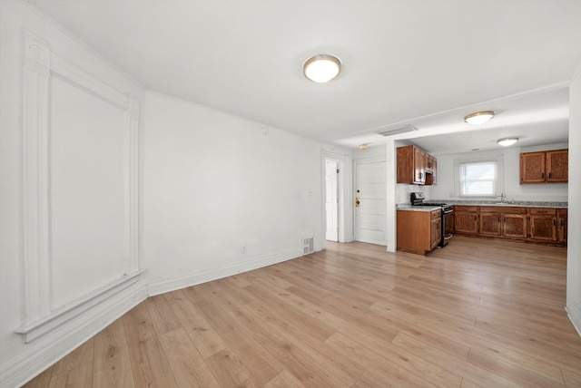 kitchen with sink, light wood-type flooring, and stainless steel gas range