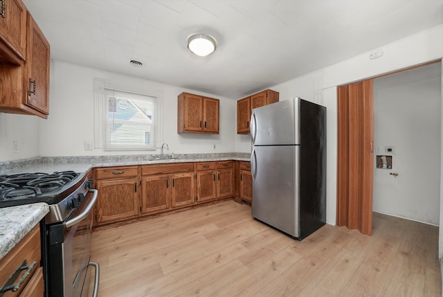 kitchen with light hardwood / wood-style flooring, stainless steel appliances, and sink