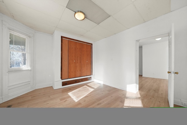 empty room with light hardwood / wood-style floors and a drop ceiling