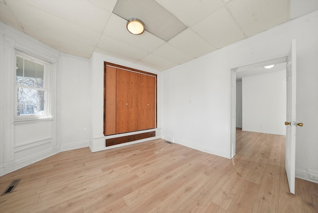 spare room with a paneled ceiling and light hardwood / wood-style flooring