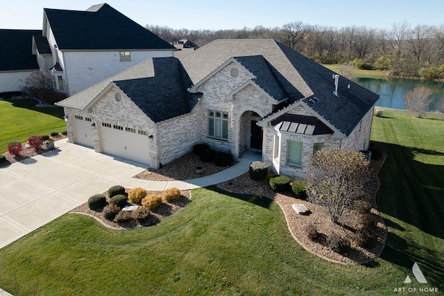 view of front of home with a front yard, a water view, and a garage