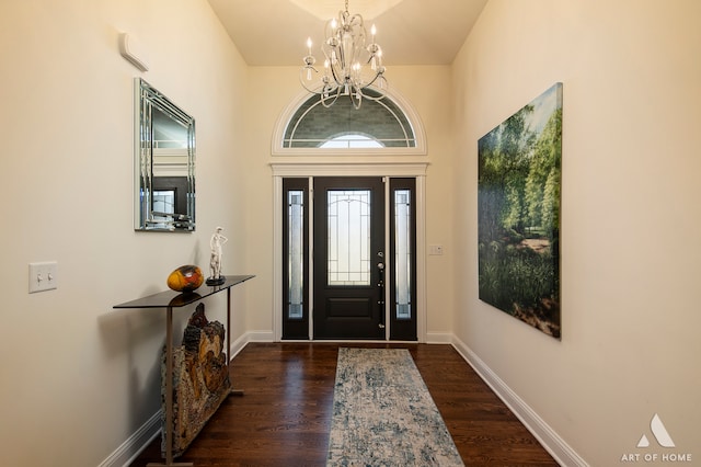 foyer with a towering ceiling, dark wood-type flooring, and a chandelier