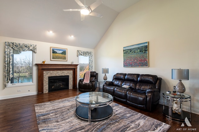 living room featuring a stone fireplace, a wealth of natural light, dark hardwood / wood-style flooring, and vaulted ceiling