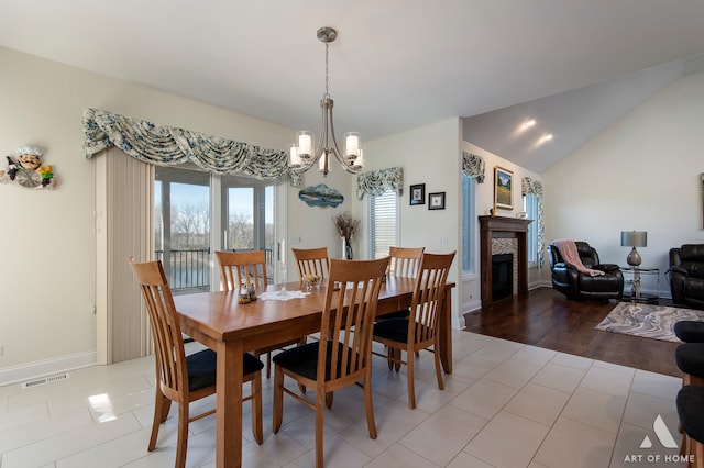 dining space with light hardwood / wood-style floors, an inviting chandelier, and vaulted ceiling