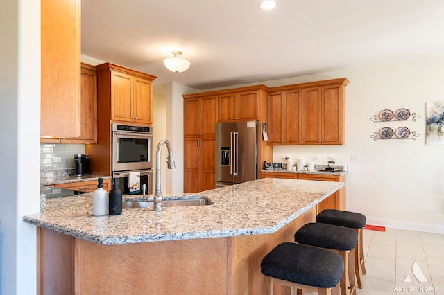 kitchen featuring sink, stainless steel appliances, light stone counters, a kitchen bar, and light tile patterned floors