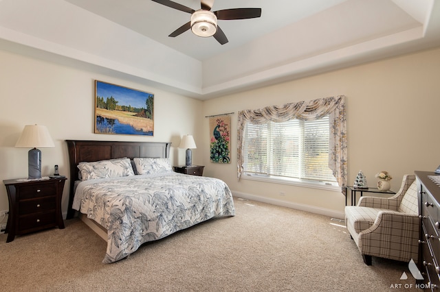 carpeted bedroom with ceiling fan and a tray ceiling