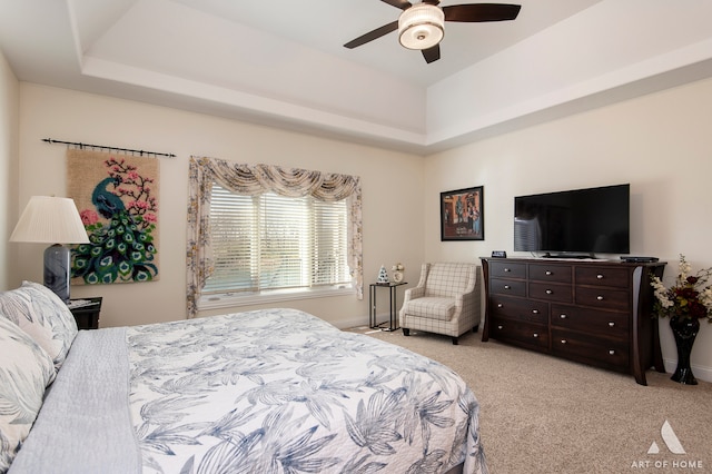 carpeted bedroom with ceiling fan and a raised ceiling