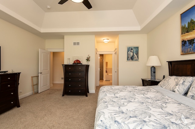 carpeted bedroom featuring connected bathroom, a tray ceiling, and ceiling fan